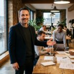 hombre sonriendo explica diagramas a equipo cooperativo
